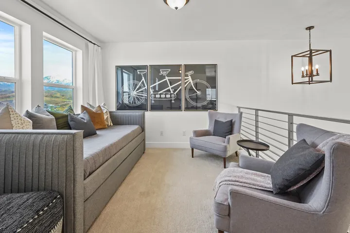 Living area with light colored carpet and suspended lighting