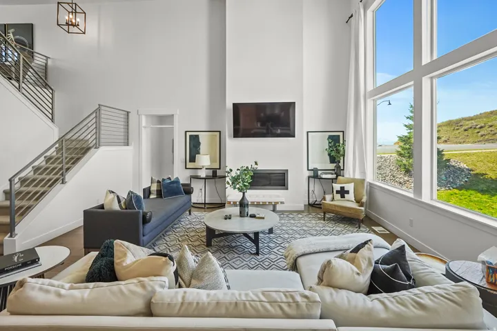 Living area featuring a high ceiling, wood finished floors, and a glass covered fireplace