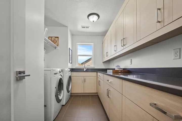 Laundry room featuring cabinet space, separate washer and dryer, a textured ceiling, and dark tile patterned floors