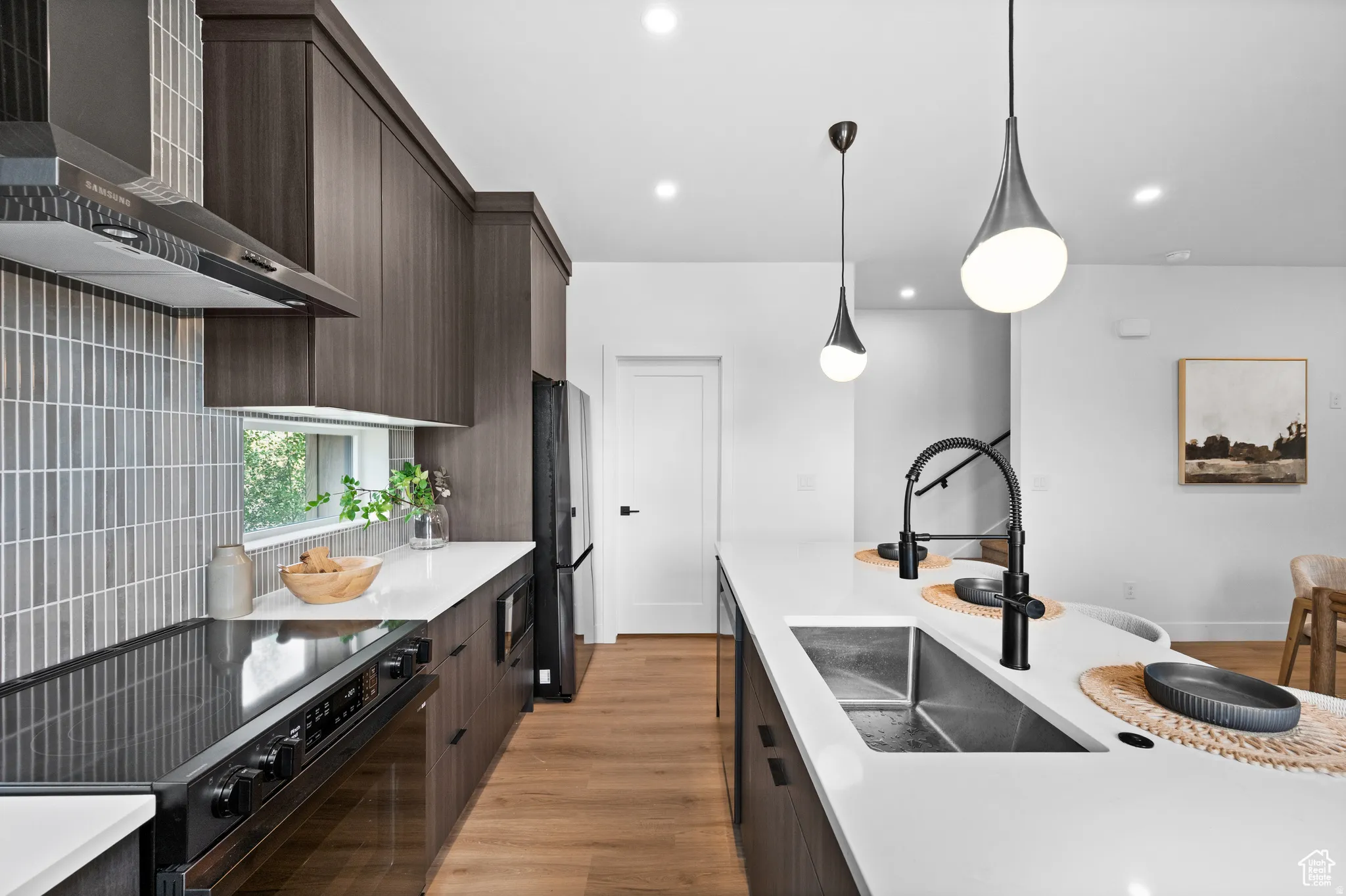Kitchen featuring black appliances, light wood finished floors, dark wood finish cabinets, and modern cabinets
