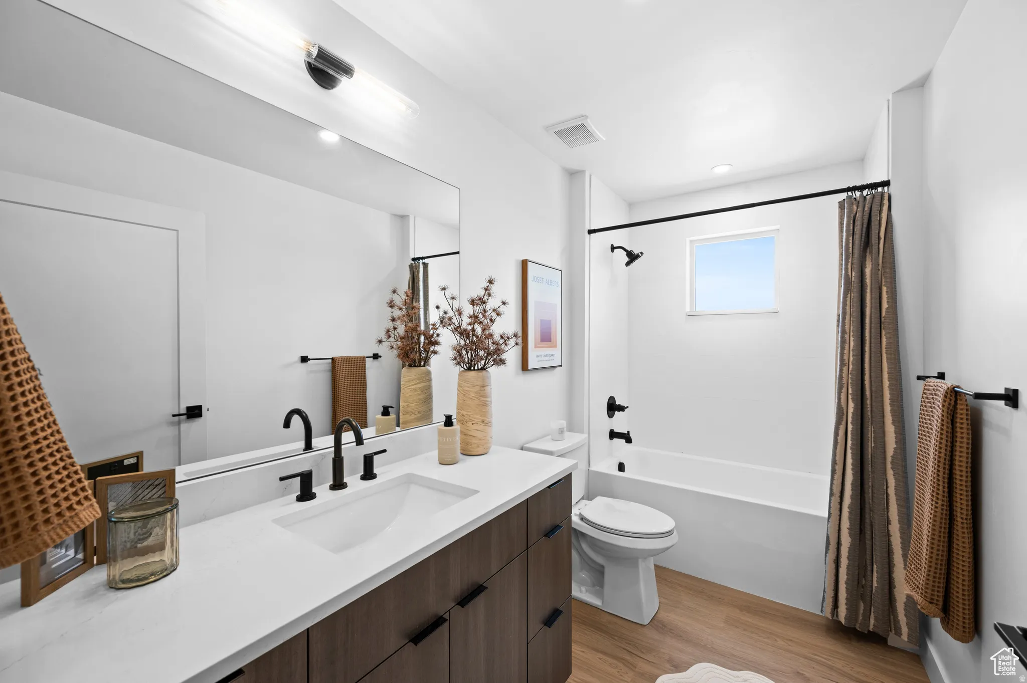 Full bathroom featuring vanity, shower / tub combo, and light wood-type flooring