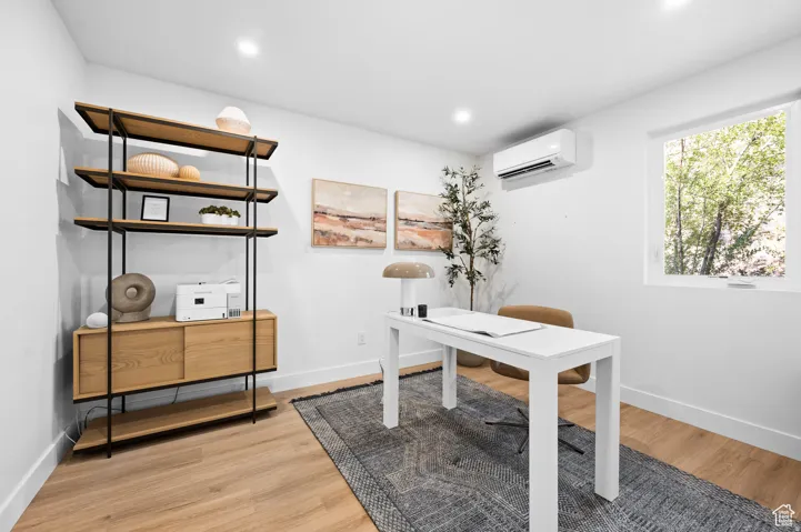 Home office with light wood finished floors and recessed lighting