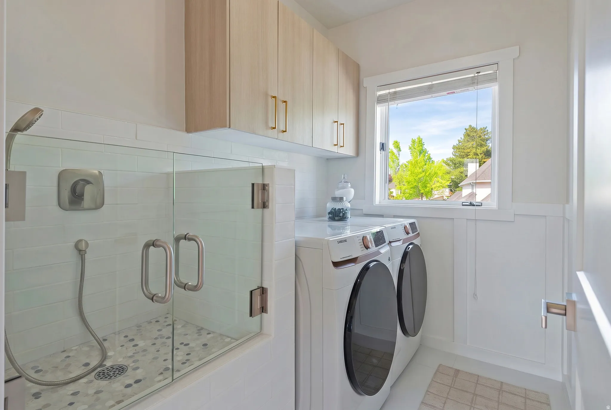 Laundry room with wainscoting, dog wash, independent washer and dryer, and cabinet space