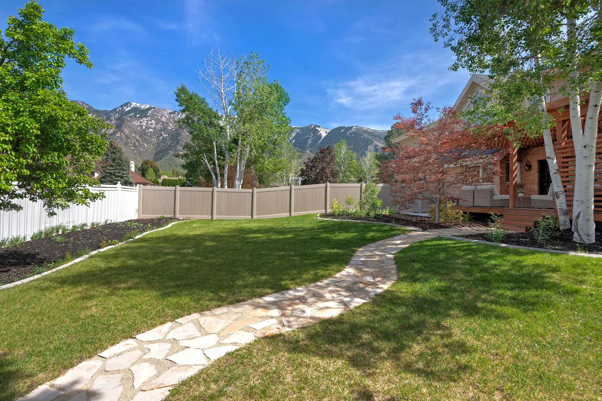 Fenced backyard featuring a deck with mountain view