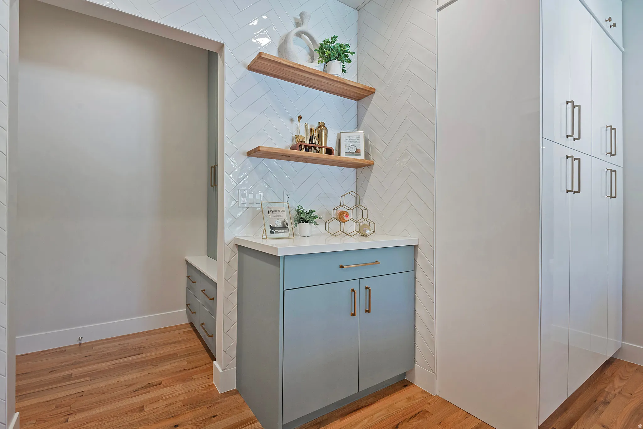 Bar featuring open shelves, light stone counters with mud room and lockers right off garage.