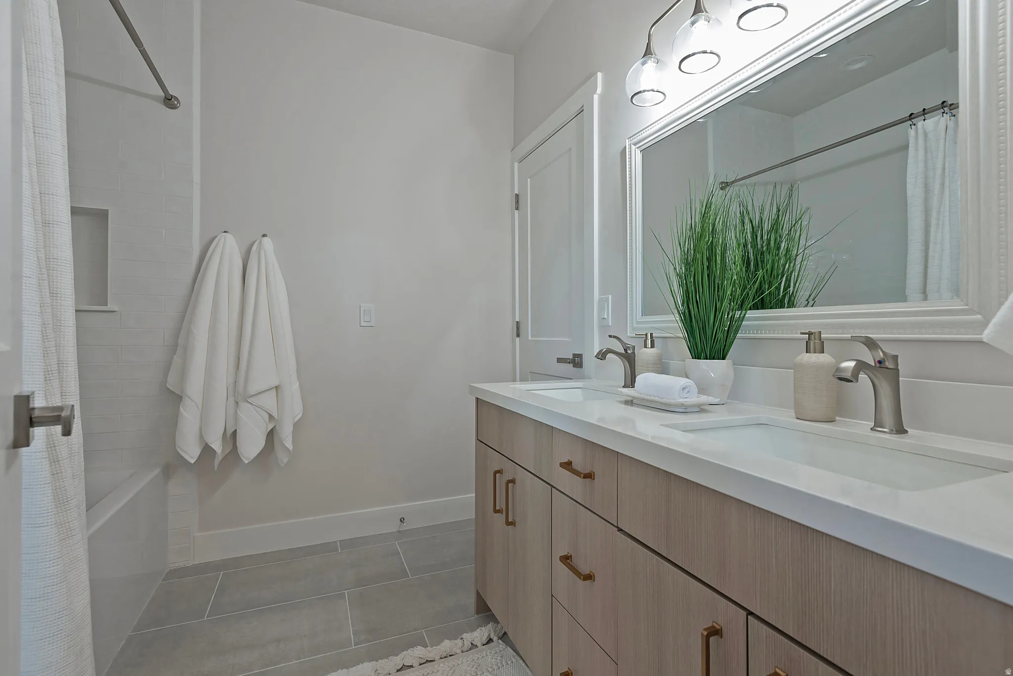Full bath featuring double vanity, shower / tub combo, and dark tile patterned flooring