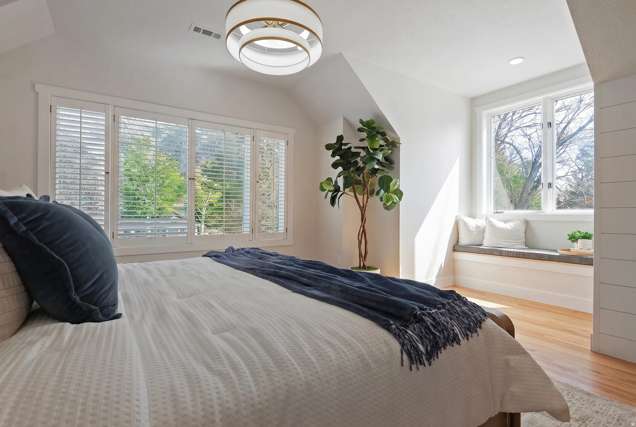 Oversized En suite primary Bedroom featuring vaulted ceiling, multiple windows, and bench seating.
