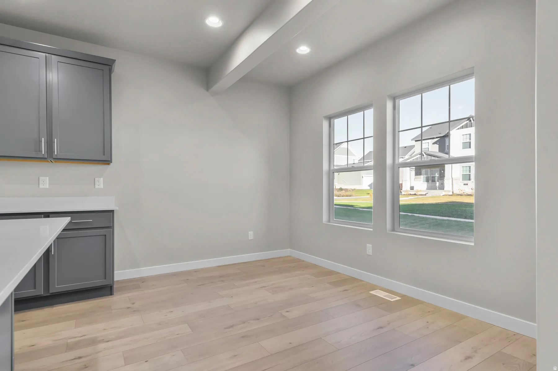 Bright interior space featuring light wood-finish flooring, recessed lighting, and dual gridded windows