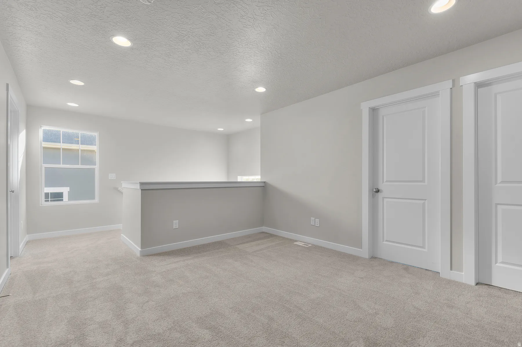 Upper-level landing featuring neutral carpeting, recessed lighting, white trim, and a window with white sills