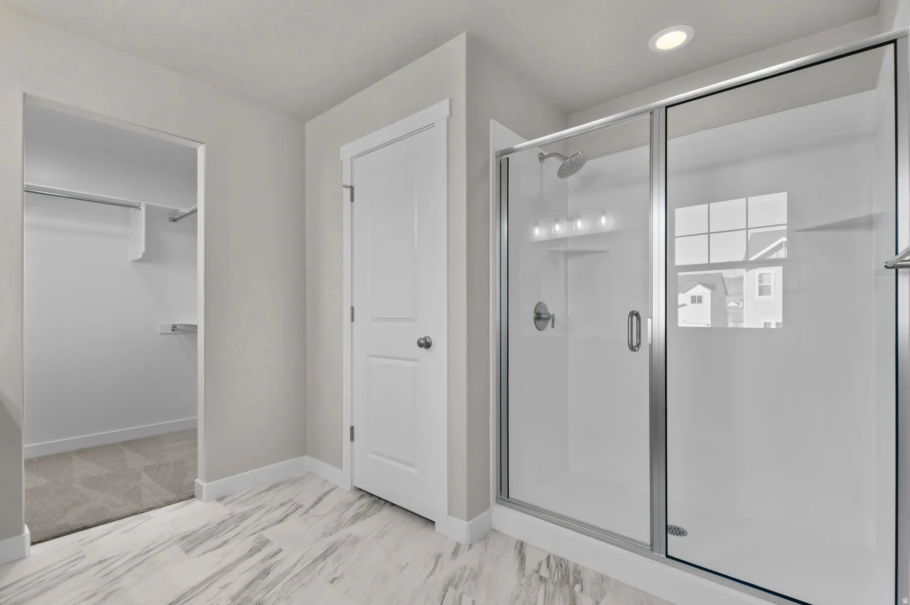 Walk-in shower with clear glass enclosure and chrome fixtures