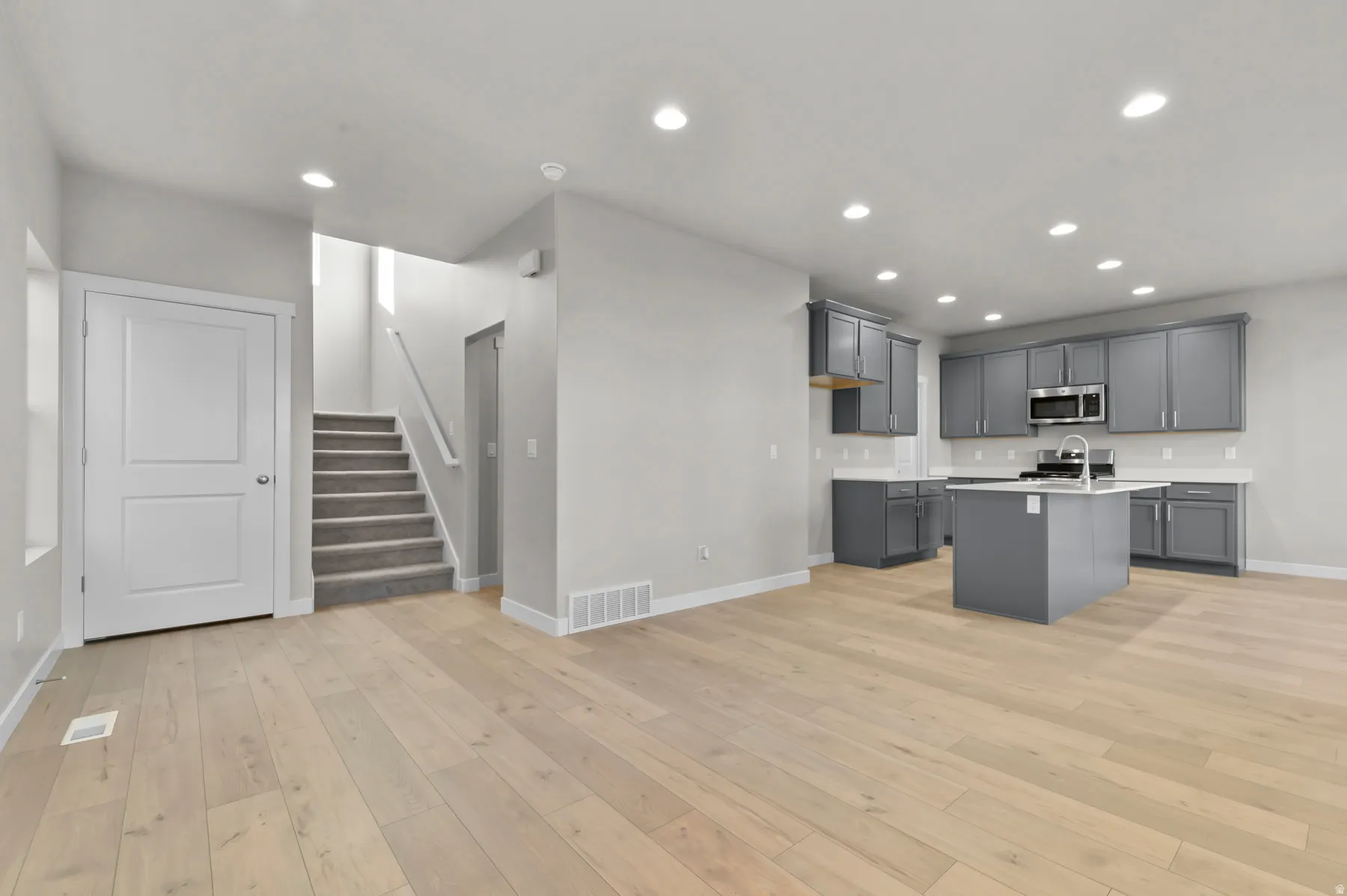 Open-concept living space featuring wood-finish flooring, recessed lighting, and a modern kitchen
