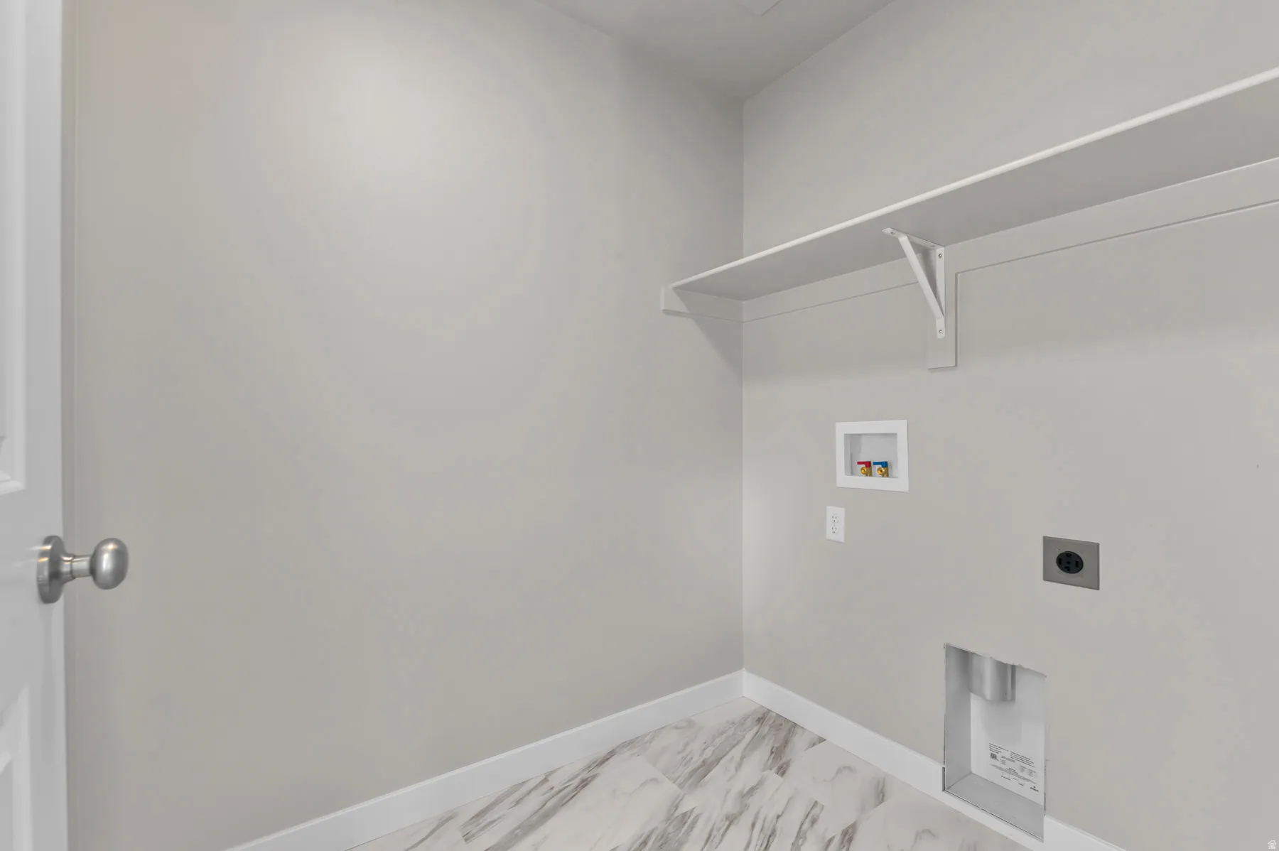 Utility area featuring a white door, light gray wall paint, and marble-look tile flooring