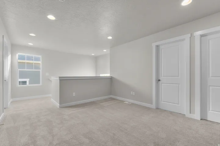 Upper-level landing featuring neutral carpeting, recessed lighting, white trim, and a window with white sills