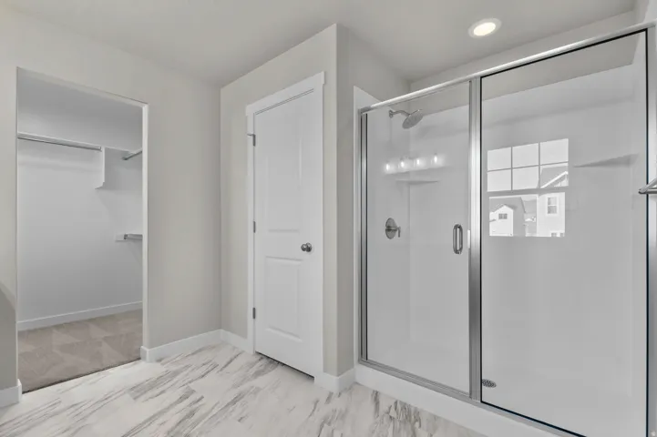 Walk-in shower with clear glass enclosure and chrome fixtures