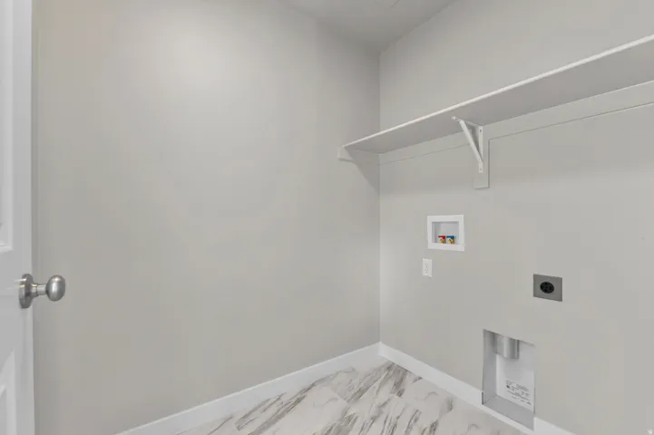 Utility area featuring a white door, light gray wall paint, and marble-look tile flooring
