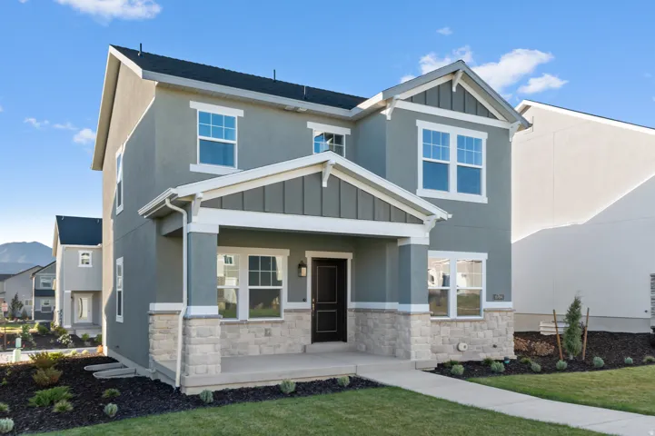 Two-story stucco residence featuring a covered front porch and stone veneer detailing