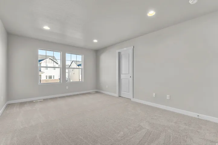 Spacious room featuring light gray walls, plush gray carpet flooring, and white baseboards
