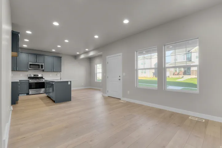 Open-concept living space with light wood-finish flooring, recessed ceiling lighting, and multiple windows