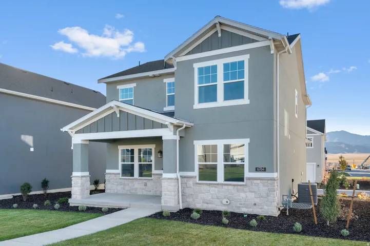 Contemporary two-story exterior featuring a covered front porch with stone veneer accents and a light gray stucco finish