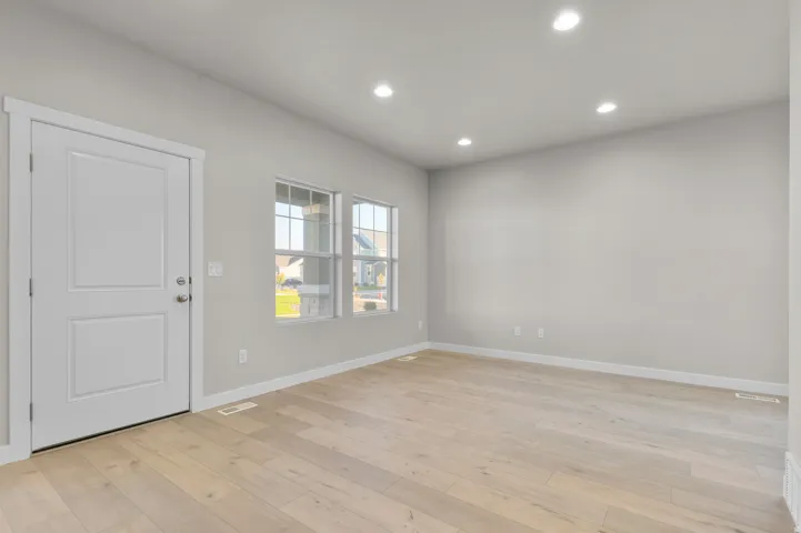 Spacious room featuring light wood-finish flooring, light gray walls, and recessed ceiling lighting