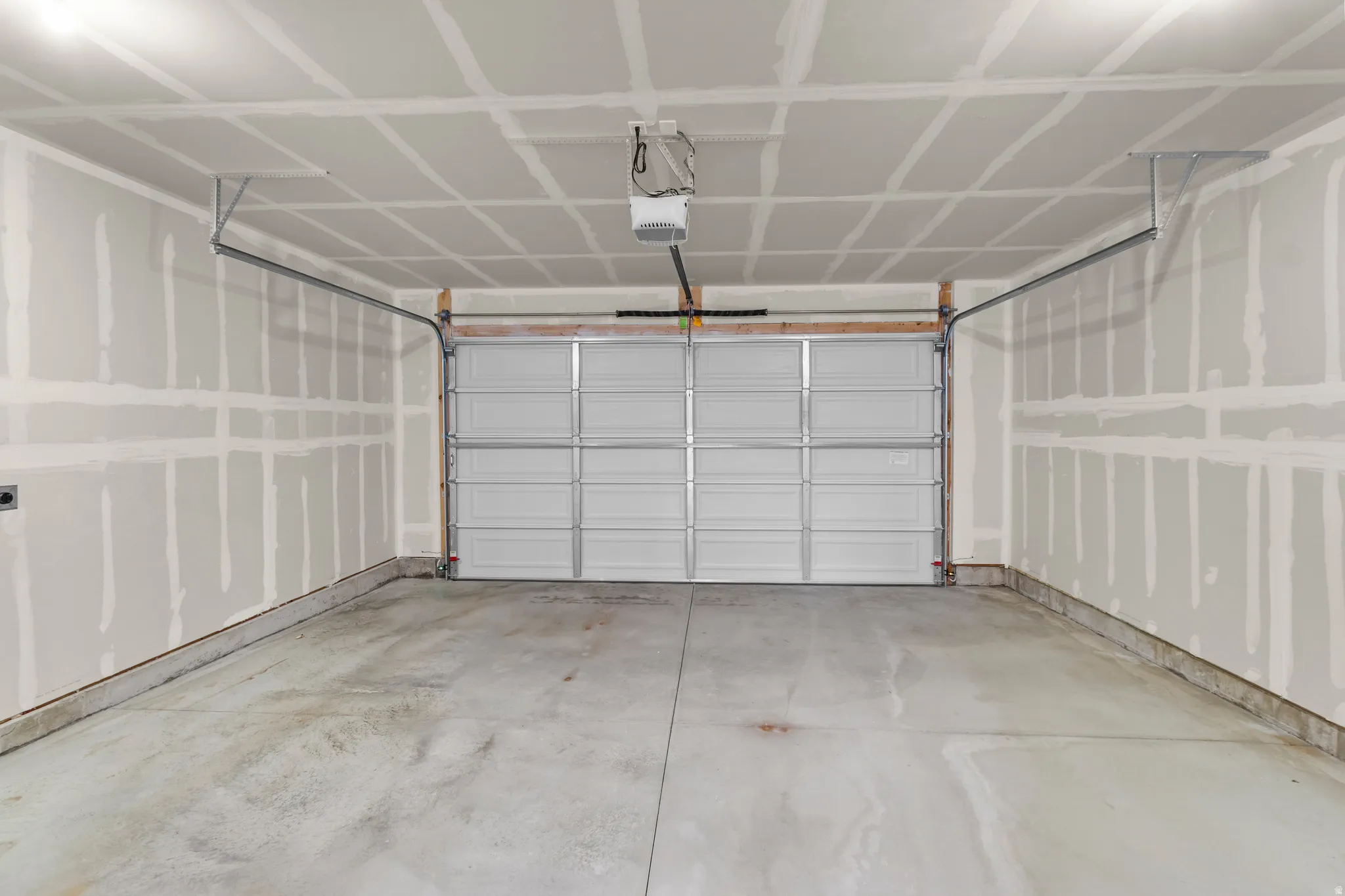 Spacious two-car garage featuring a concrete floor, an overhead garage door, and an automatic garage door opener