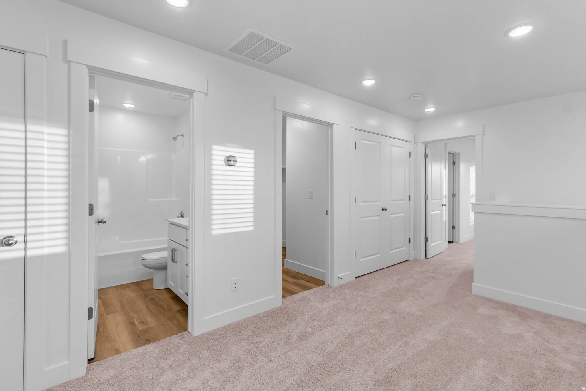 Full bathroom featuring a white tub/shower combination, white vanity, and wood-finish flooring