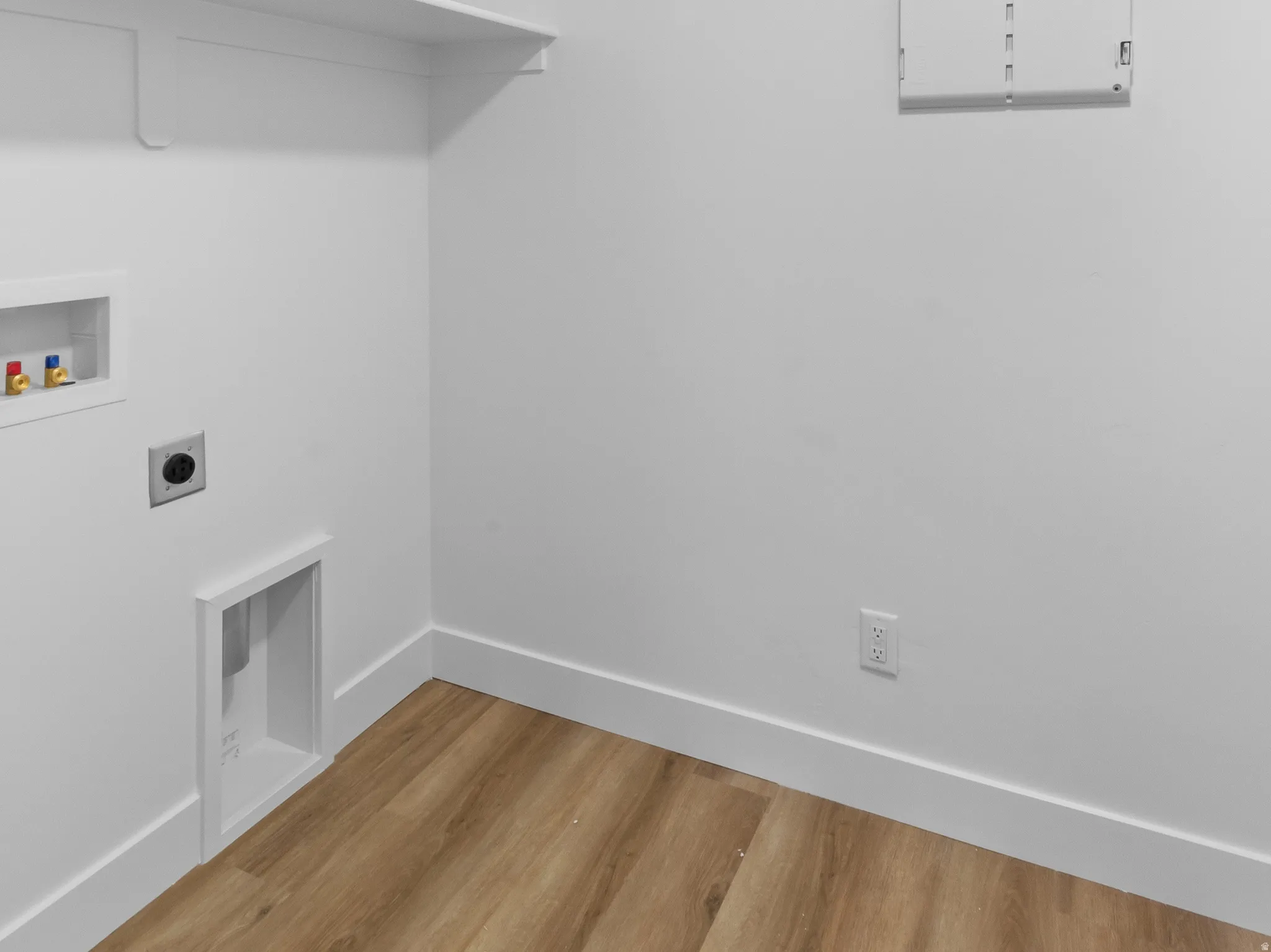 Dedicated laundry area featuring wood-finish flooring, white walls, and a recessed ceiling access panel