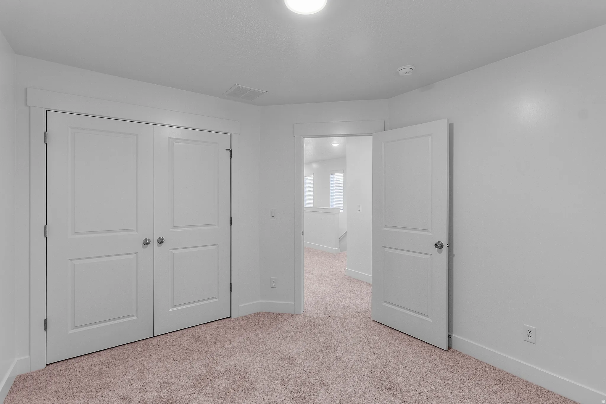 Wall-to-wall carpeting in a neutral tone complements the white walls and trim