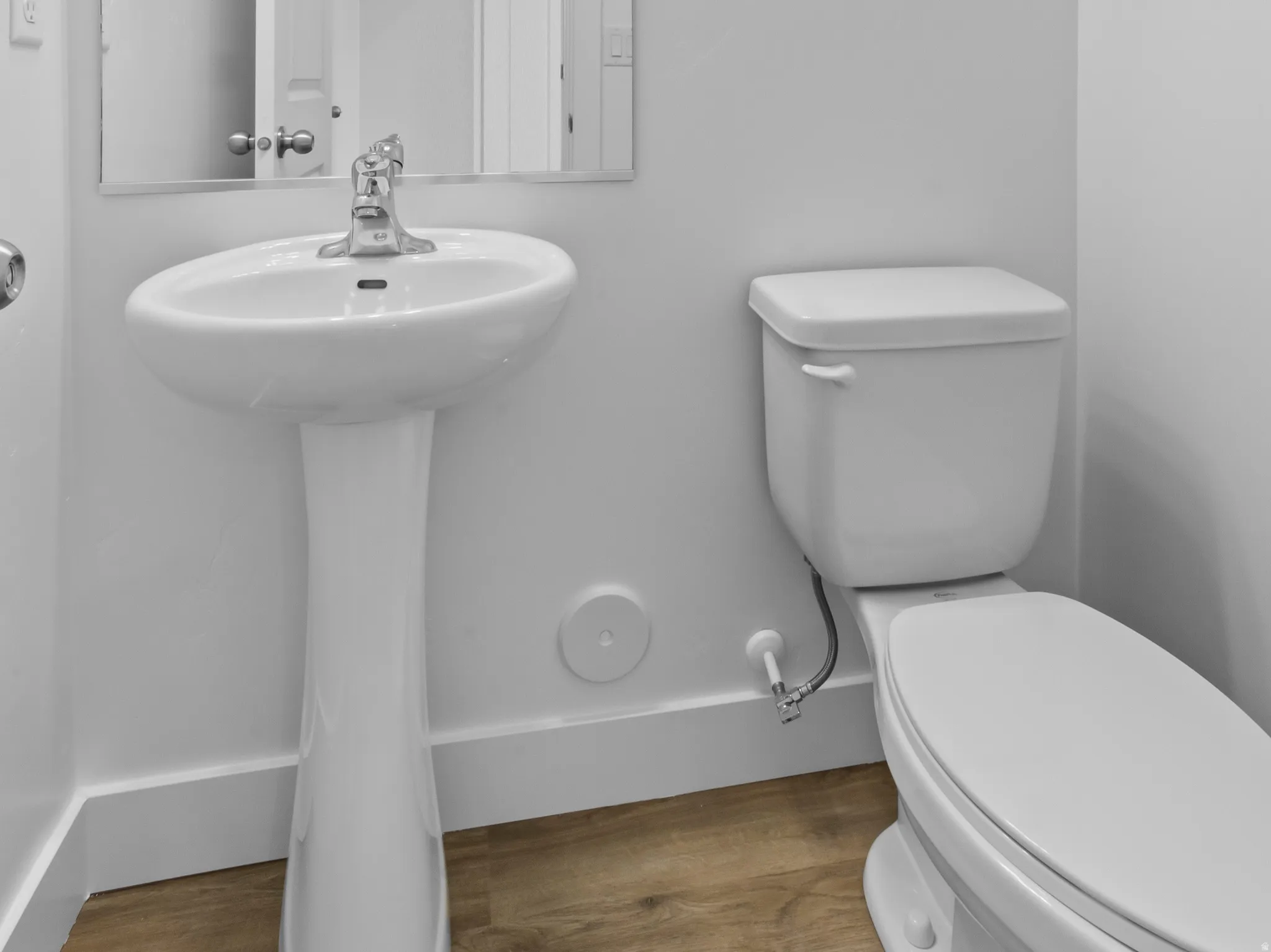 Pedestal sink with chrome faucet, complemented by a rectangular mirror and a three-light vanity fixture