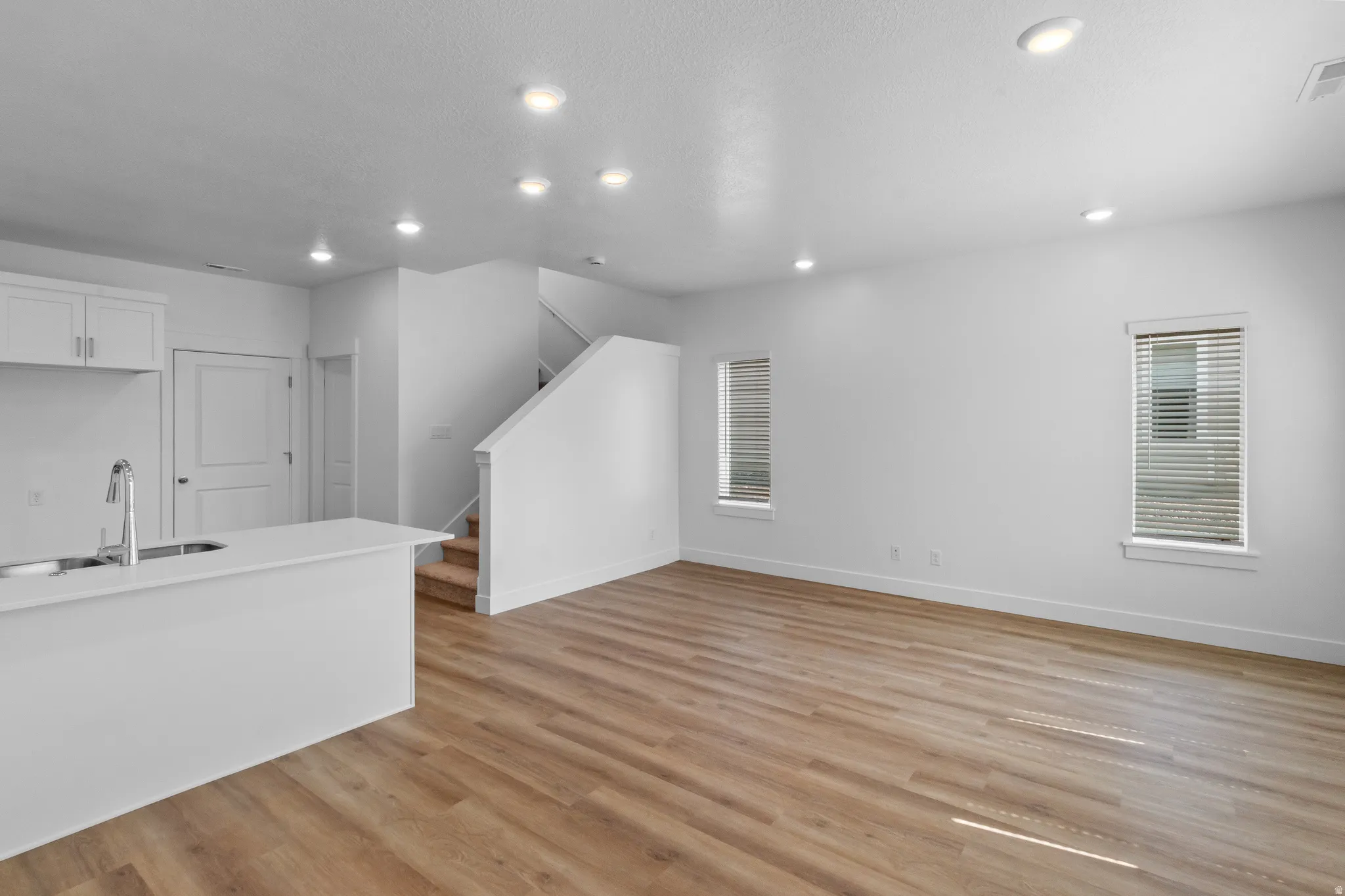 Open-concept living space featuring wood-finish flooring, recessed lighting, and bright white walls