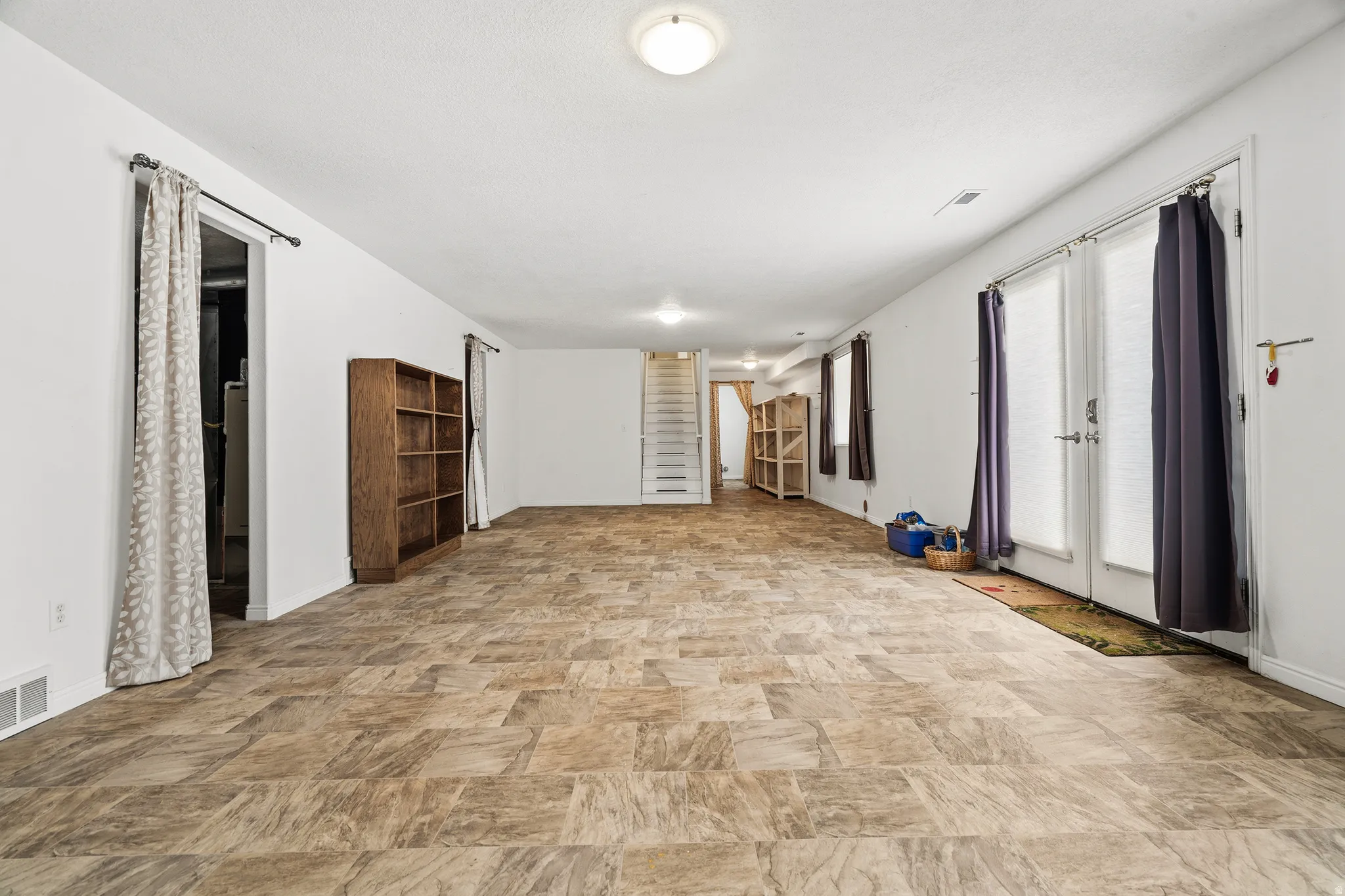 Spacious room featuring tile-finish flooring and white painted walls
