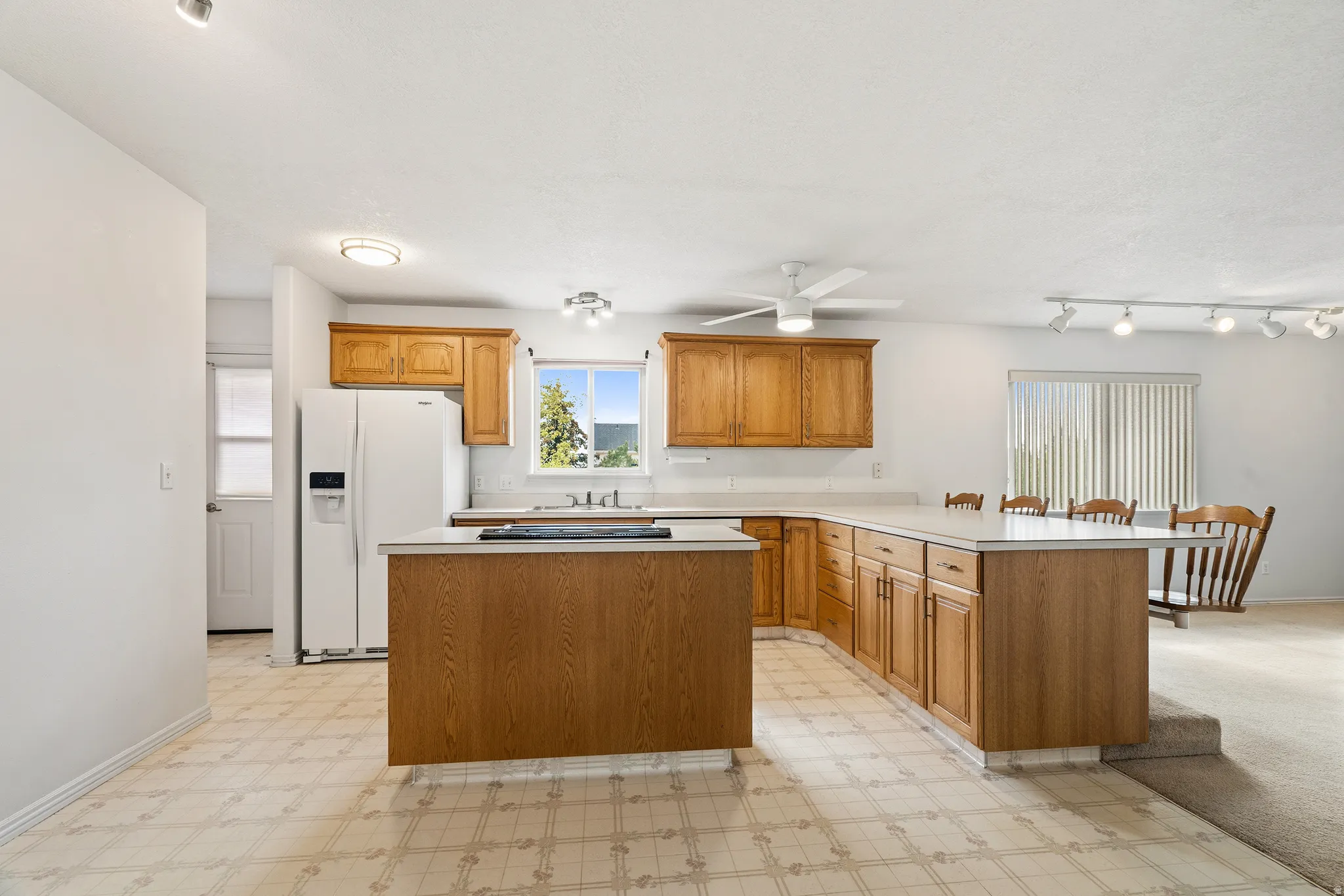 Kitchen featuring wood-finish cabinetry, white countertops, built-in refrigerator, and a kitchen island