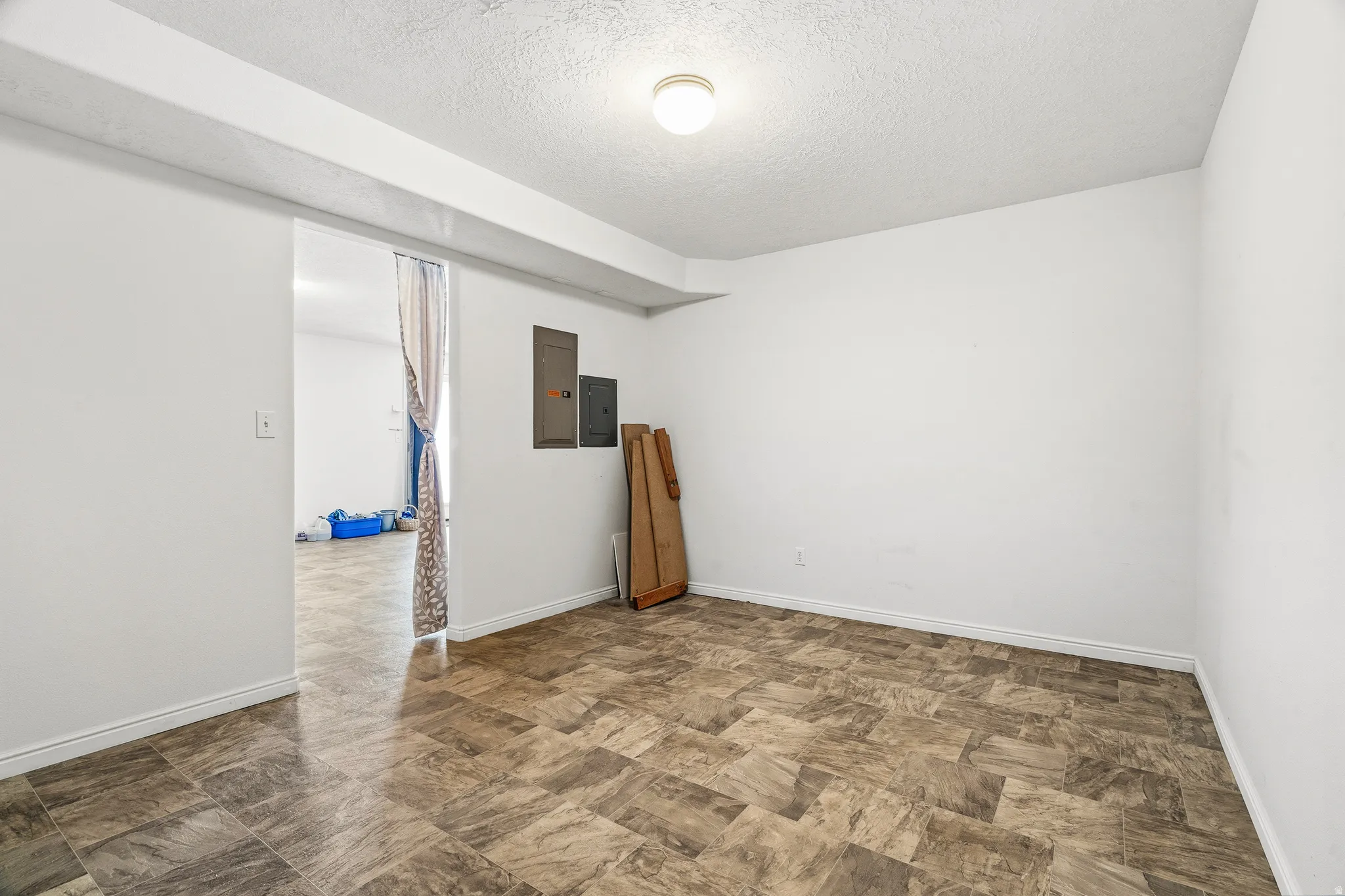 Spacious room featuring patterned flooring, white walls, and a ceiling-mounted light fixture
