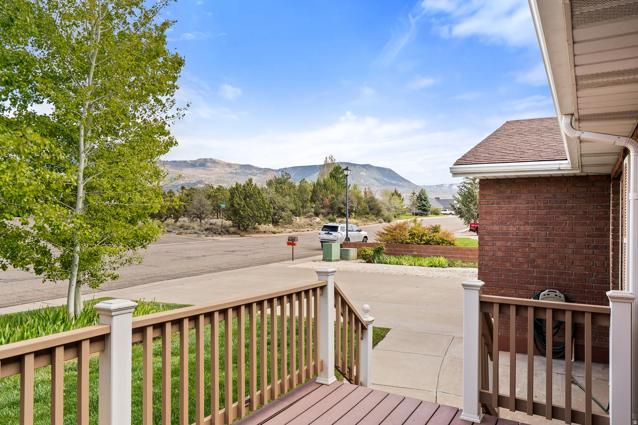 Front porch featuring wood-finish decking and railing with white posts