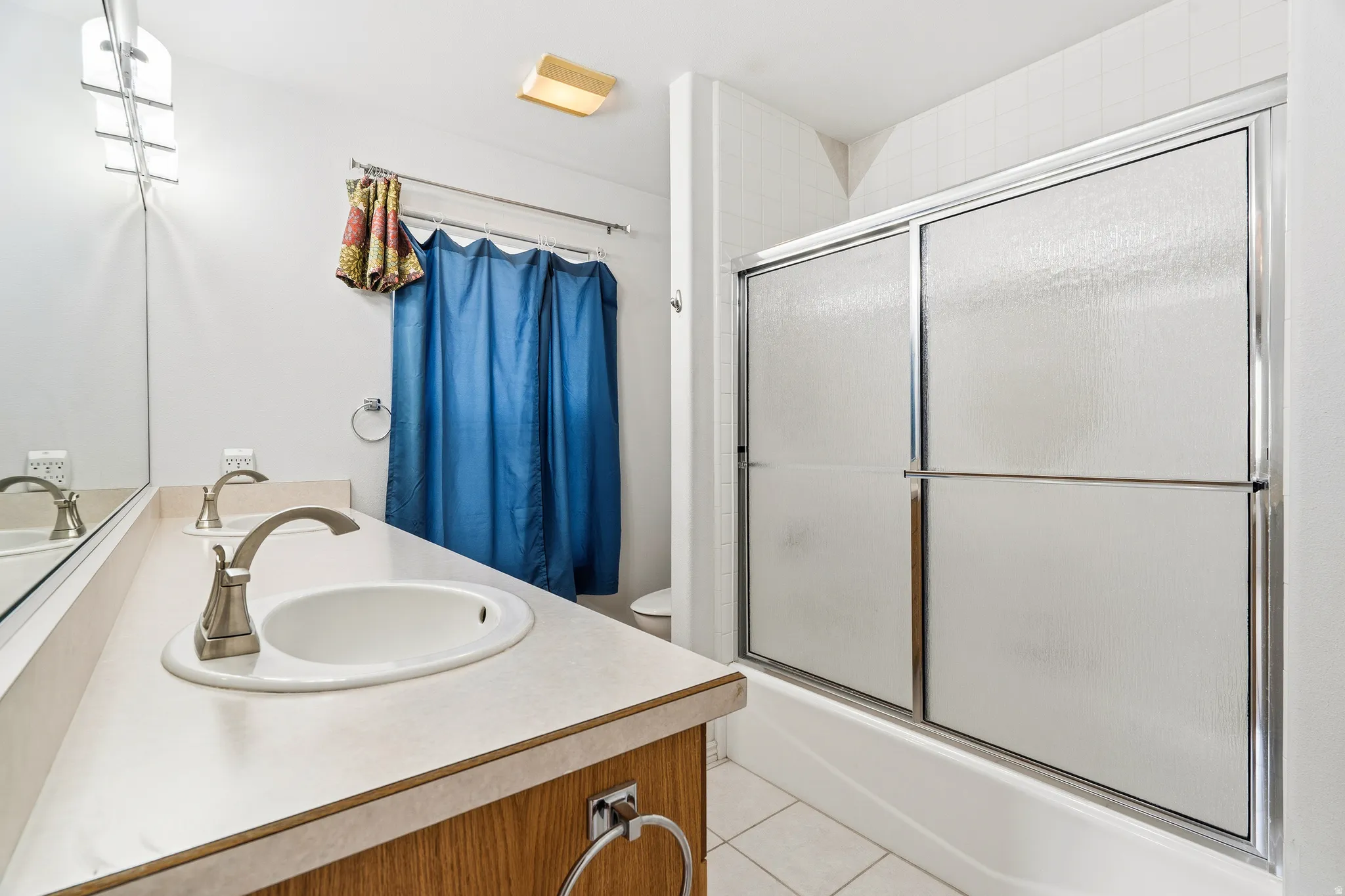 Bathroom featuring a double vanity with integrated sinks, brushed nickel faucets, and a full-width wall mirror