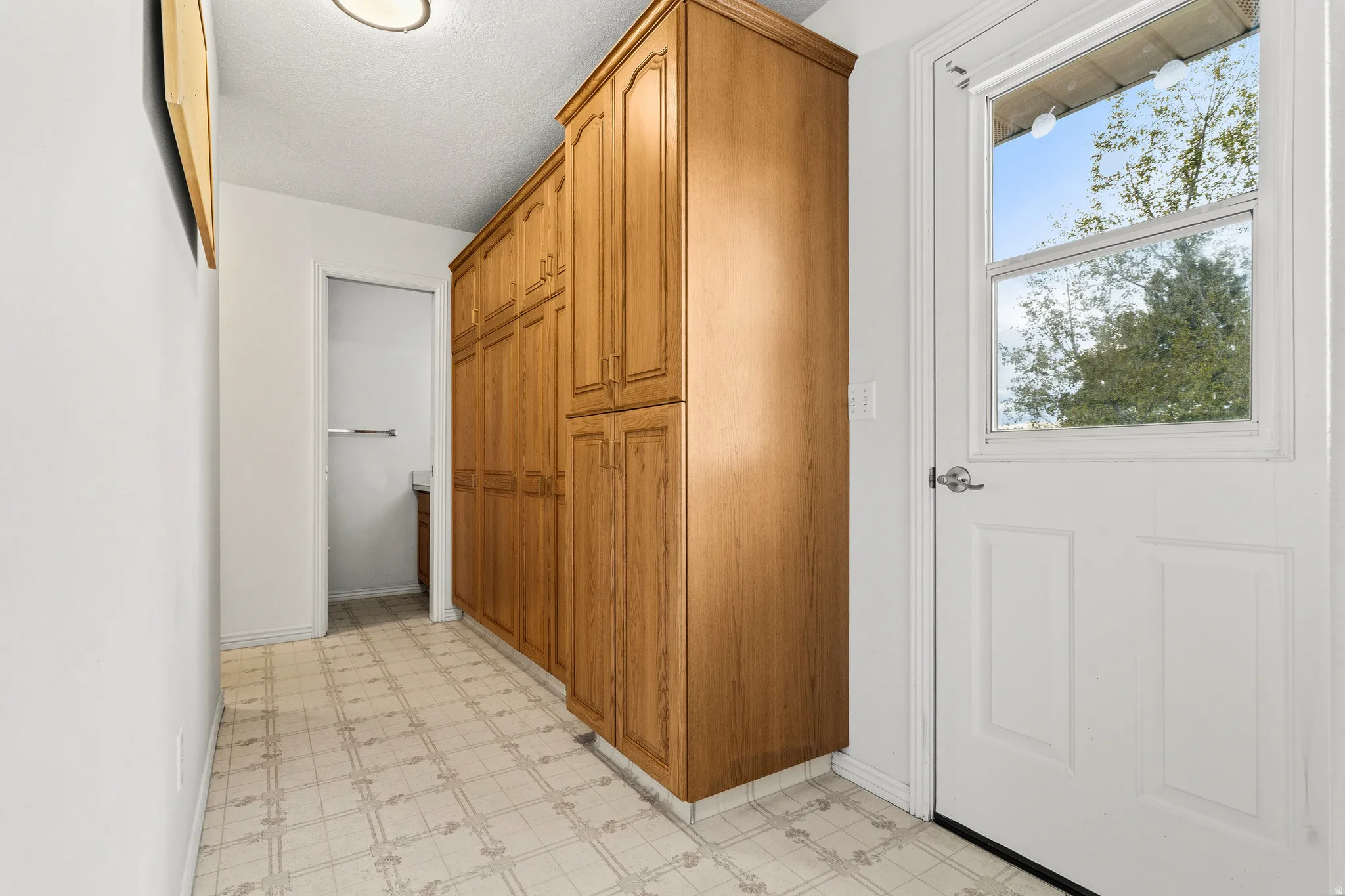 Hallway featuring extensive wood-finish cabinetry, patterned flooring, and a white paneled door with an integrated window