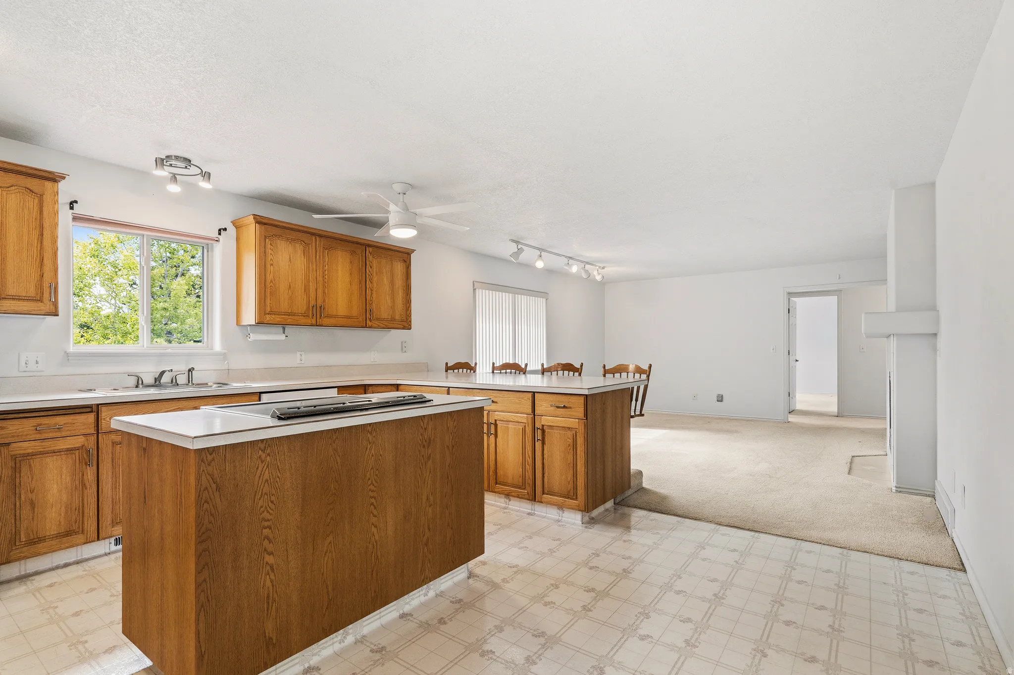 Kitchen featuring wood cabinetry, white countertops, and a central island with an integrated cooktop