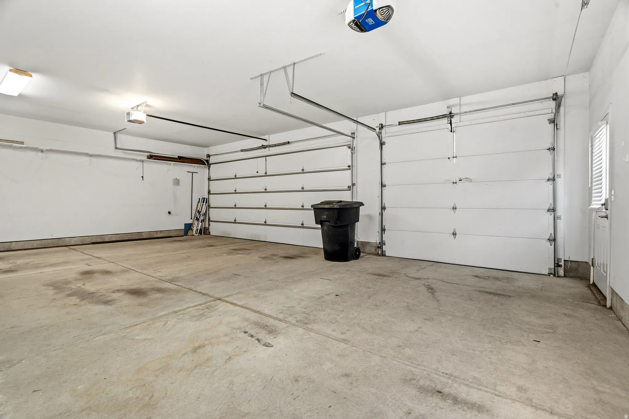 Spacious garage featuring two overhead doors, an automatic garage door opener, concrete flooring, and an interior access door