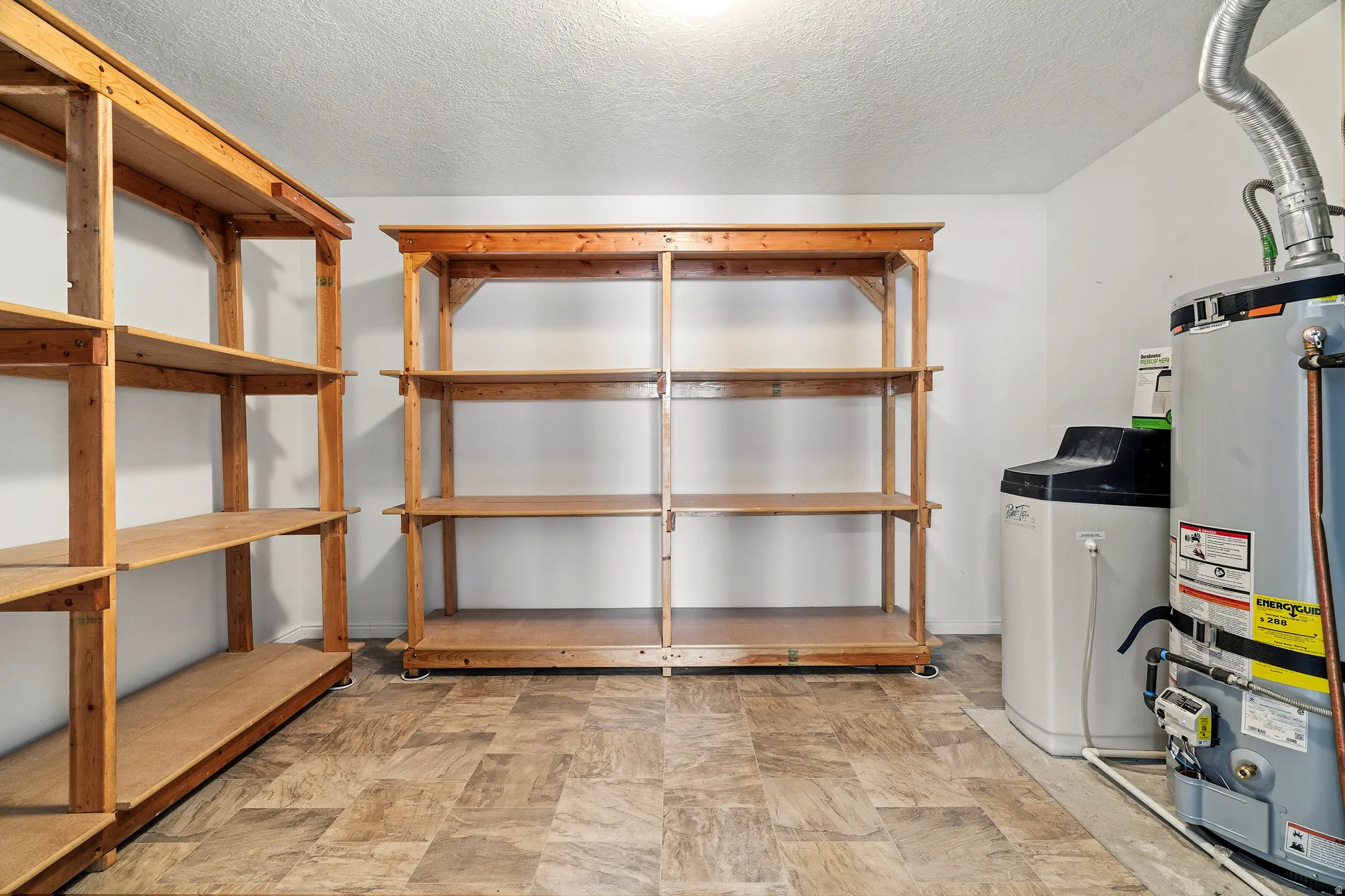 Utility space featuring built-in wooden shelving, a water heater, and a water softener system