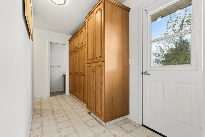 Hallway featuring extensive wood-finish cabinetry, patterned flooring, and a white paneled door with an integrated window