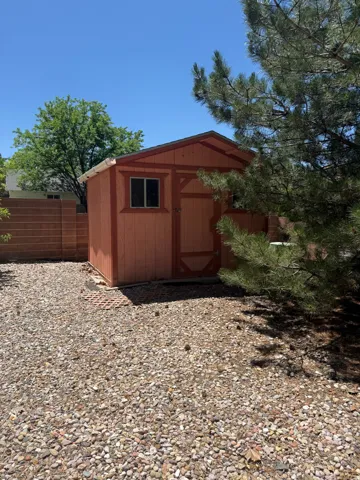 Freestanding storage shed with a shingle roof and a functional window