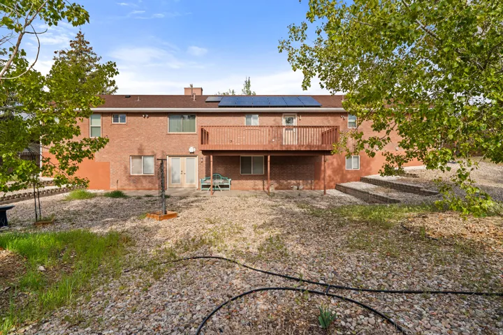 Brick exterior featuring a second-story wooden deck, ground-level patio doors, and solar panels