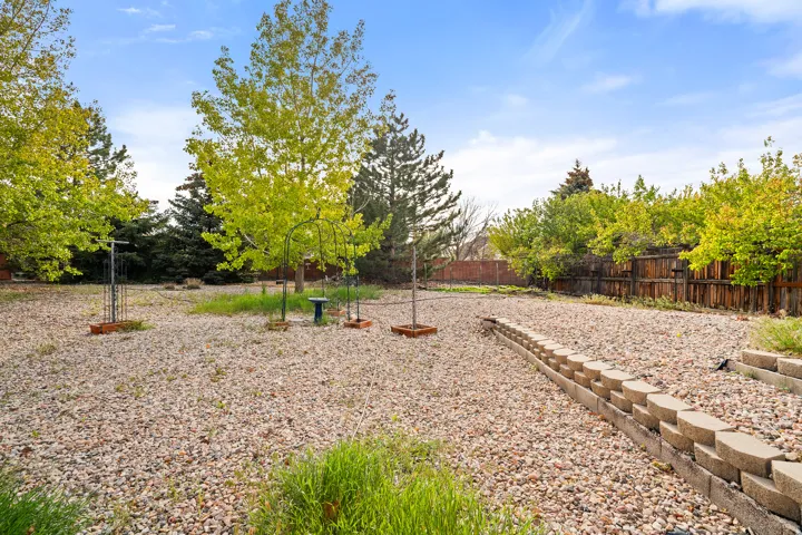 Expansive outdoor area featuring a gravel ground cover, mature trees, and a wooden perimeter fence