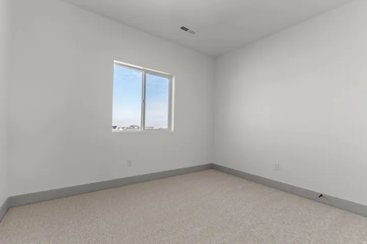 Bright room featuring a single window, light-colored carpeting, white walls, and gray baseboards