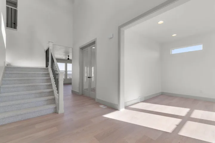 Two-story entryway featuring wood-finish flooring, a carpeted staircase with a black metal and white wood railing, and a window for natural illumination