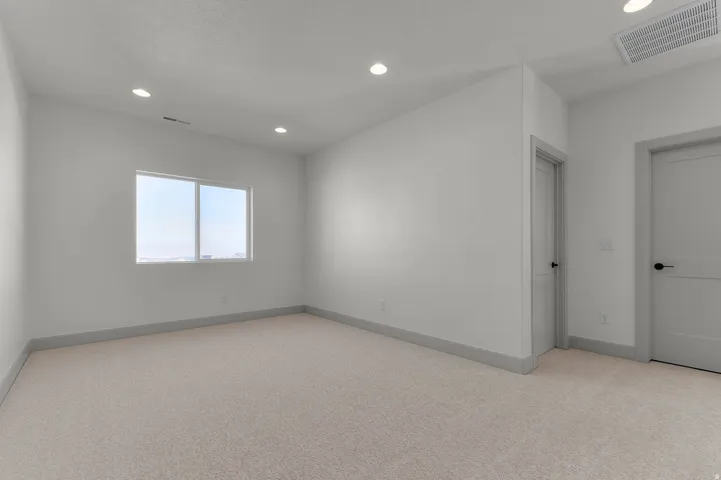 Carpeted room with a double-pane window, recessed lighting, and two interior doors with black hardware