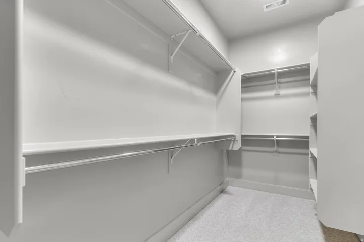 Spacious walk-in closet featuring extensive wire shelving, multiple hanging rods, and an integrated built-in shelving unit