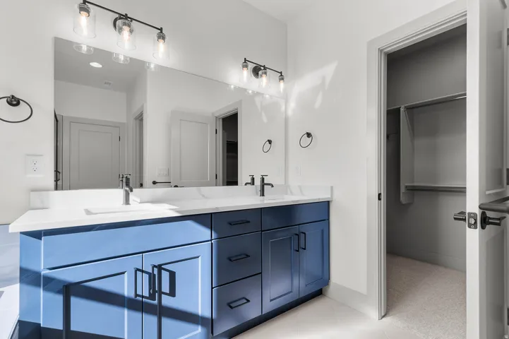 Dual vanity with a white countertop and blue cabinetry