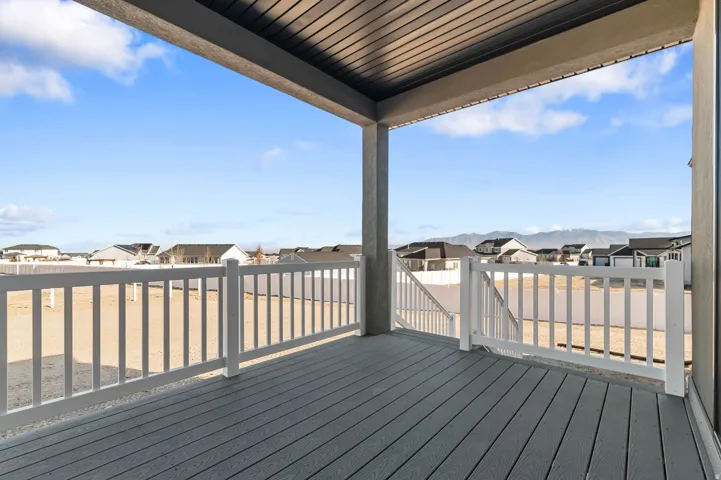 Covered deck with composite decking and white railing, featuring a clear sky and distant mountain backdrop