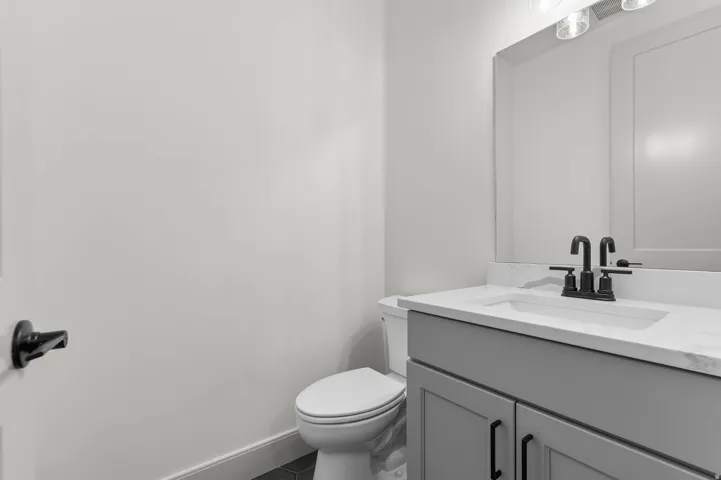 Modern bathroom featuring a single vanity with a light gray cabinet, white countertop, and matte black faucet